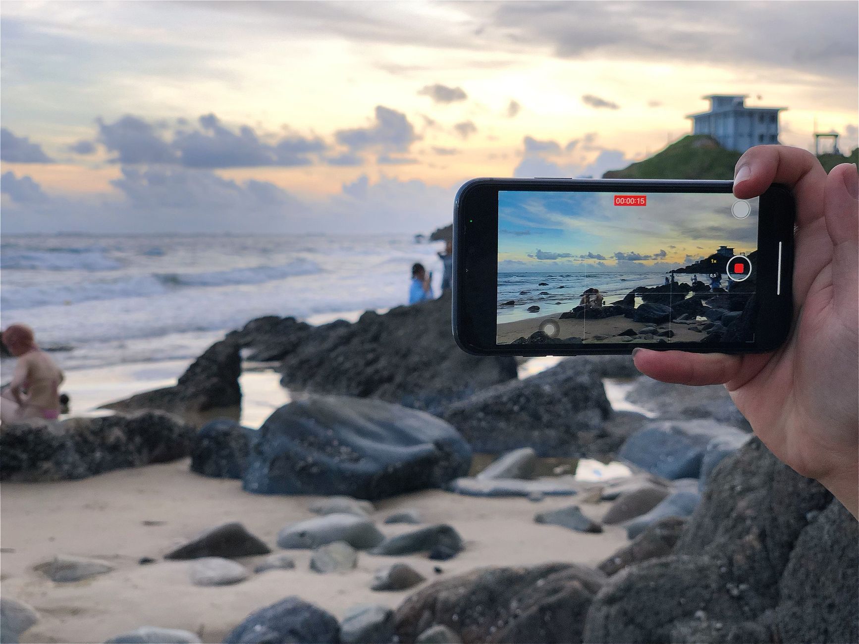 Smartphone displaying vertical 9:16 travel video reel of ocean sunset at luxury resort
